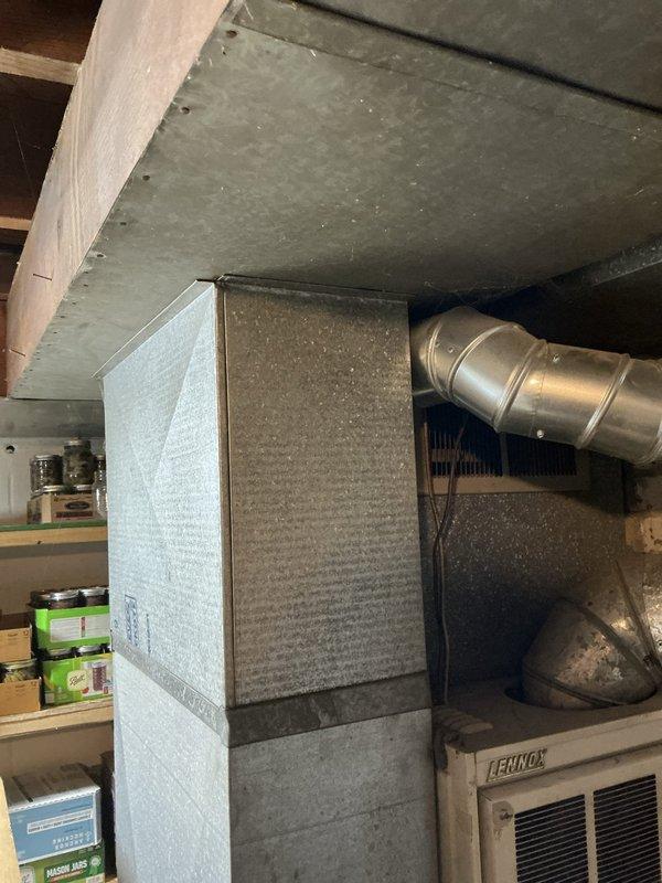 Conducted on-site estimate for furnace and water heater replacement in residential property. Assessed existing approximately 50-year-old furnace system and aging water heater located in basement utility area. Documented current equipment conditions including Lennox brand HVAC unit with existing galvanized metal ductwork, return air plenum, and white cylindrical water heater with top-mounted flue connections. Photographed mechanical room layout, existing duct configurations, and equipment placement to develop accurate replacement proposal. Evaluated structural considerations including exposed ceiling insulation, wooden support beams, and available clearances for new equipment installation.