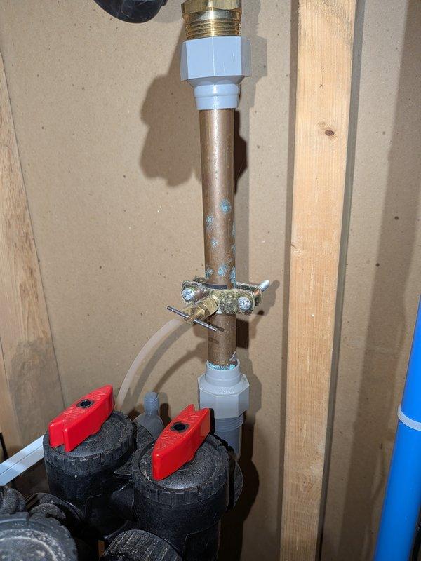 Responded to report of water leak in basement ceiling potentially originating from 14-year-old Payne air conditioning system. Upon inspection, examined copper pipe assembly with brass fittings, white plastic connectors, and shutoff valves in affected area. Investigated crawl space above basement where horizontal piping runs alongside structural beams. Observed water staining and discoloration on ceiling surfaces near pipe routing. Documented plumbing connections, condensate drain line, and surrounding structural components. Photographed copper piping, drainage assembly with shutoff valves, and overhead pipe installation to establish current system condition and identify potential leak source points.