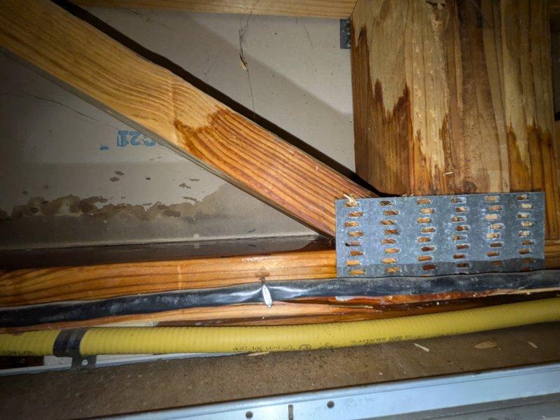 Responded to report of water leak in basement ceiling potentially originating from 14-year-old Payne air conditioning system. Upon inspection, examined copper pipe assembly with brass fittings, white plastic connectors, and shutoff valves in affected area. Investigated crawl space above basement where horizontal piping runs alongside structural beams. Observed water staining and discoloration on ceiling surfaces near pipe routing. Documented plumbing connections, condensate drain line, and surrounding structural components. Photographed copper piping, drainage assembly with shutoff valves, and overhead pipe installation to establish current system condition and identify potential leak source points.