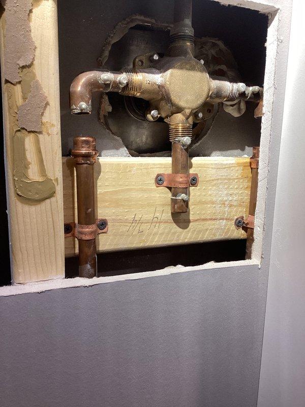 Replaced both shower valves requiring drywall access to reach the plumbing assembly behind the wall. Installed new brass shut-off valves with hot and cold water controls, connected to existing copper supply lines, and secured all connections to wooden backing. Completed repairs with clean access panels in cabinet space, restoring full water control functionality to the shower system.