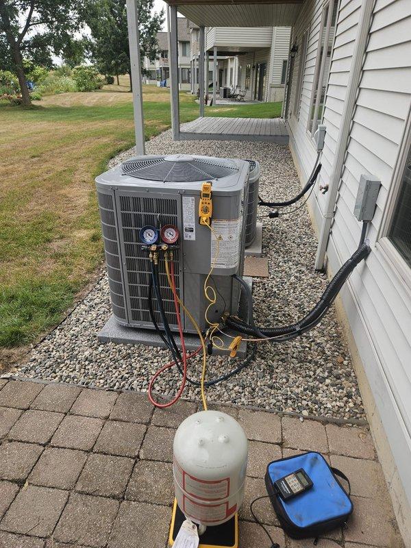 Completed full air conditioning system replacement at residential property. Removed existing HVAC equipment and installed new furnace unit in basement mechanical room with proper PVC intake and exhaust venting routed vertically. Installed new outdoor condenser unit on gravel pad adjacent to building exterior with proper refrigerant line connections secured to siding. Performed refrigerant recovery procedures using manifold gauges and recovery cylinder to properly evacuate and charge system to manufacturer specifications. Verified all electrical connections at panel box, tested system operation, and confirmed proper airflow through existing ductwork. All equipment installed per code requirements and manufacturer guidelines with system fully operational upon completion.