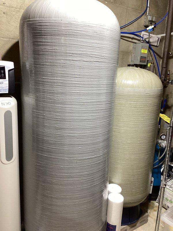 Responded to service call for inspection of complex residential water treatment system. Upon arrival, evaluated multi-component setup including multiple water softener tanks, whole-house filtration system with wall-mounted filter cartridge assembly, pressure storage tank, and interconnected plumbing infrastructure. Documented system configuration with photographs showing N2O-labeled softener units, blue filter housing, copper piping network, pressure gauges, control boxes, and chemical treatment bottles. Assessed system complexity and serviceability to determine if equipment falls within company's scope of maintenance capabilities.