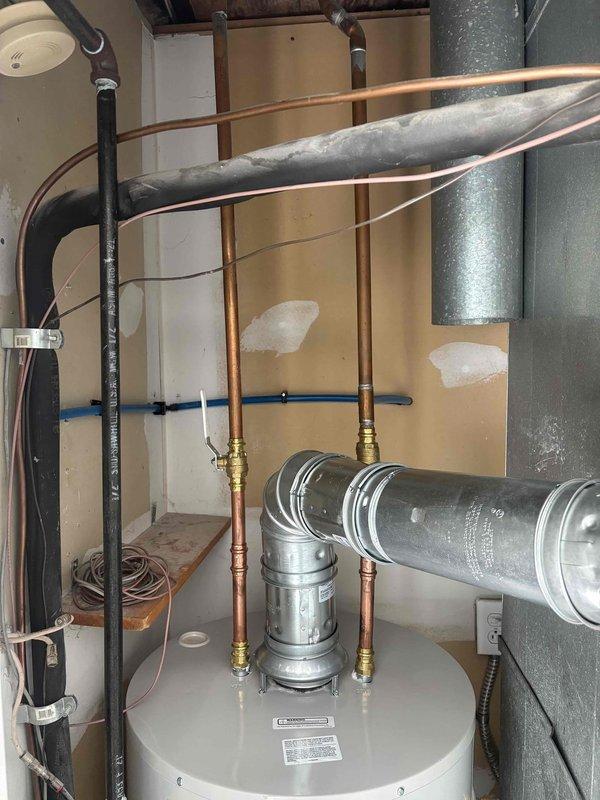Completed installation of a 40-gallon natural gas water heater with 6-year warranty and short tank configuration in utility room. Connected copper supply lines with brass fittings, integrated unit with existing plumbing infrastructure including insulated pipes and HVAC ductwork, and secured all connections to ensure proper operation and code compliance.