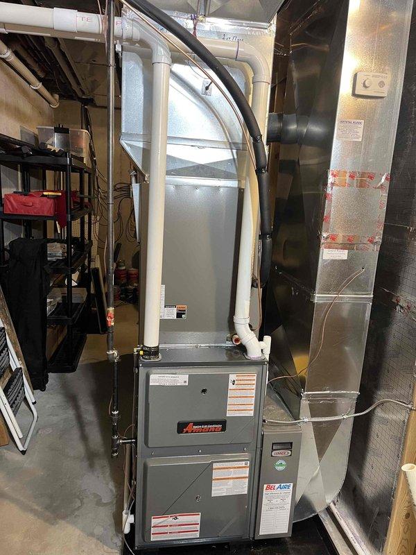 Successfully completed full installation of new Amana furnace and Bradford White water heater in basement utility room. Furnace installation included proper mounting of gray cabinet unit, connection of supply and return ductwork, installation of white PVC intake and exhaust venting routed through ceiling joists, and complete electrical hookup with all manufacturer specifications verified. Water heater installation included positioning of new Bradford White unit, connection of copper supply and discharge lines with shut-off valves and brass fittings, installation of temperature and pressure relief valve, proper flue pipe installation for venting, and verification of all safety labels and energy guide documentation. All plumbing connections tested for leaks, gas connections pressure tested and verified, electrical connections confirmed operational, and both units fired up and tested for proper operation. System left in full working order with all manufacturer labels intact and visible.