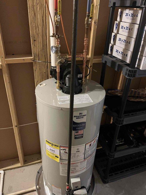 Successfully completed full installation of new Amana furnace and Bradford White water heater in basement utility room. Furnace installation included proper mounting of gray cabinet unit, connection of supply and return ductwork, installation of white PVC intake and exhaust venting routed through ceiling joists, and complete electrical hookup with all manufacturer specifications verified. Water heater installation included positioning of new Bradford White unit, connection of copper supply and discharge lines with shut-off valves and brass fittings, installation of temperature and pressure relief valve, proper flue pipe installation for venting, and verification of all safety labels and energy guide documentation. All plumbing connections tested for leaks, gas connections pressure tested and verified, electrical connections confirmed operational, and both units fired up and tested for proper operation. System left in full working order with all manufacturer labels intact and visible.