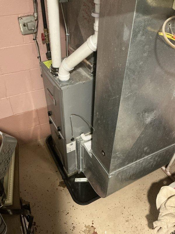 Responded to customer complaint of air conditioning unit running but not cooling to set temperature on a 10-year-old system. Performed diagnostic evaluation of HVAC equipment located in basement utility area. Inspected furnace unit, ductwork, electrical connections, and associated components including PVC condensate piping and air return plenum. Documented equipment condition and installation setup with photographic evidence showing gray metal furnace against cinder block wall, exposed electrical wiring, and overall system configuration. Provided estimate for necessary repairs to restore proper cooling functionality.