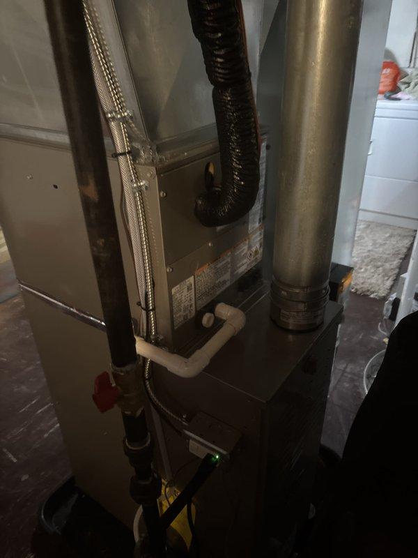 Completed full HVAC system installation including new furnace, air conditioning unit, and water heater in residential basement utility area. All ductwork connections secured and tested, including vertical metal supply ducts and flexible return air ducting. PVC condensate drainage lines installed with proper pitch and gas supply lines connected with shutoff valve. All equipment positioned for optimal airflow and service accessibility, with manufacturer specifications verified and system commissioned for operation.