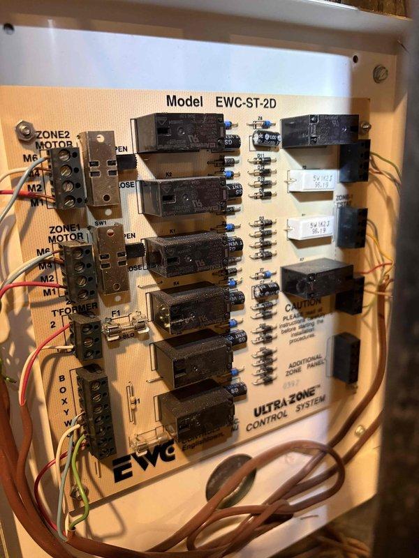 Responded to no cooling call for residential HVAC system with 22-year-old air conditioner and 16-year-old Amana furnace. Inspected basement mechanical room installation including electrical panel, EWC Ultra Zone Control System (Model EWC-ST-2D), condensate drainage assembly, and refrigerant line set. Documented existing two-zone motor control system with relay modules and terminal connections, along with current equipment configuration and electrical components mounted on utility room wall.