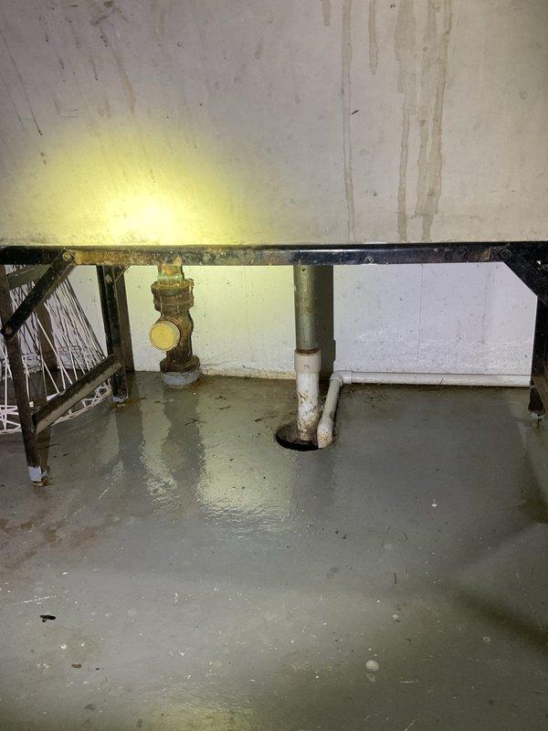 Responded to emergency call for basement drain clog with active flooding. Upon arrival, found extensive standing water throughout basement utility room, with water several inches deep covering concrete floor and affecting storage areas. Located main floor drain with blockage causing backup and overflow. Cleared obstruction from drain line to restore proper drainage flow. Verified water was draining correctly through system after clearing blockage. Documented pre-existing water damage conditions including floor saturation and wall staining from the flooding event.