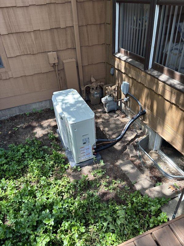 Completed full installation of residential furnace and air conditioning system. New outdoor condensing unit was positioned on concrete pad with proper refrigerant line connections utilizing black insulated piping. Indoor furnace unit was installed with all necessary electrical disconnects, copper refrigerant lines with brass fittings and service valves, and white PVC condensate drainage piping. System was charged, tested, and verified operational with diagnostic readings recorded on equipment access panel. All components properly mounted to building exterior with cedar shake siding, ensuring code-compliant installation and optimal system performance.