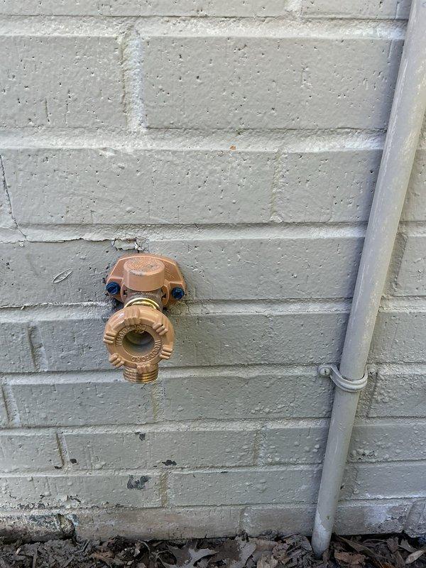 Responded to plumbing leak concerns involving copper piping in the basement and an outdoor frost-proof faucet. Upon inspection, identified the exterior hose bib mounted on white-painted brick/cinder block wall showing signs of age and potential failure. The brass fixture exhibited weathering and patina consistent with outdoor exposure. Documented current condition of the outdoor spigot and its mounting configuration for repair or replacement recommendation. Assessed basement copper pipe leaks to prevent further water damage and deterioration of the plumbing system.
