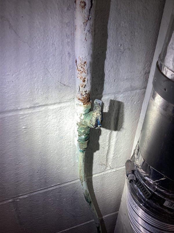 Responded to propane system pressure leak detected during installation by propane supplier. Performed pressurized leak detection on gas supply lines serving propane appliances. Located source of pressure drop in corroded copper gas piping system. Visible corrosion, rust staining, and deterioration observed on vertical supply pipe and connecting copper lines in basement utility area. Repaired compromised gas line sections to restore system integrity. System successfully pressure tested and verified leak-free operation before restoring propane supply.