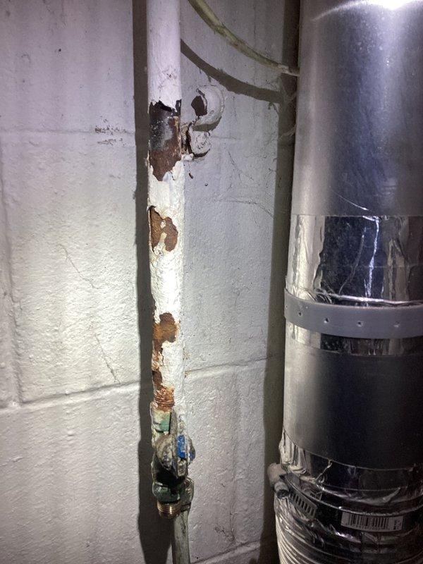Responded to propane system pressure leak detected during installation by propane supplier. Performed pressurized leak detection on gas supply lines serving propane appliances. Located source of pressure drop in corroded copper gas piping system. Visible corrosion, rust staining, and deterioration observed on vertical supply pipe and connecting copper lines in basement utility area. Repaired compromised gas line sections to restore system integrity. System successfully pressure tested and verified leak-free operation before restoring propane supply.