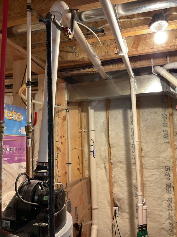 Provided estimate for water heater replacement in unfinished basement with exposed framing and existing mechanical systems. Documented current water heater installation including connections to PVC vent piping routed along ceiling joists and associated plumbing configuration. Assessed installation requirements considering spray foam insulation, HVAC ductwork, and spatial constraints within the construction area for proper equipment access and code-compliant installation.