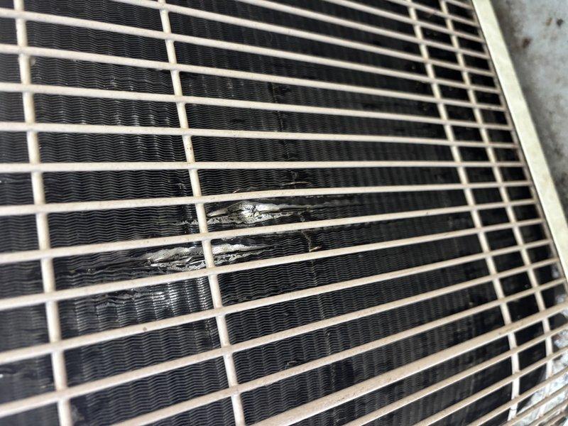 Completed annual cooling maintenance on 21-year-old Bryant air conditioning system. Performed comprehensive tune-up including inspection of outdoor condenser unit where damaged grille section with tape repair was documented, condenser coils assessed and found in acceptable condition, and interior components including refrigerant lines, PVC drainage system, and electrical connections were inspected and verified operational.