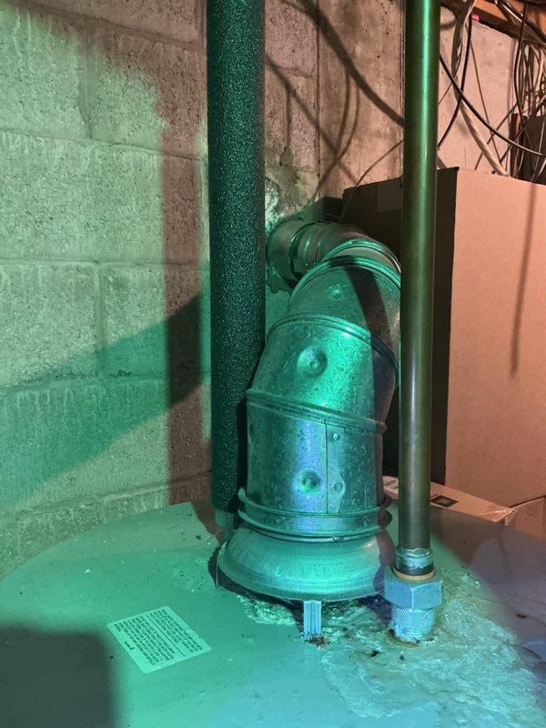 Responded to water leak reported at base of 21-year-old Lennox furnace. Upon inspection, determined leak was originating from condensate pump system rather than furnace unit itself. Photographed mechanical room showing water heater, green-painted piping system, and condensate pump assembly mounted on concrete floor. Examined pump connections and discharge piping for signs of failure or obstruction. Verified furnace heating and cooling functions remained operational despite moisture issue. Documented equipment condition and leak source for further evaluation and repair recommendations.