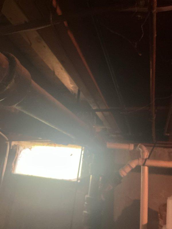 Responded to service call for non-operational sump pump in 68-year-old residential property. Upon arrival, conducted visual inspection of basement mechanical room and identified aging sump pump system with deteriorated components. Assessed plumbing infrastructure including PVC drainage lines, galvanized steel piping, and associated utility connections showing significant wear consistent with property age. Examined electrical connections including visible orange wiring and verified power supply to pump unit. Documented existing conditions of mechanical room including water heater, utility sink, concrete floor with moisture staining, and overall aging infrastructure. Inspected crawl space and attic areas to trace drainage routing and copper piping runs through structural joists. Photographed installation for service records. Identified pump failure likely due to age-related component deterioration in original mechanical system.