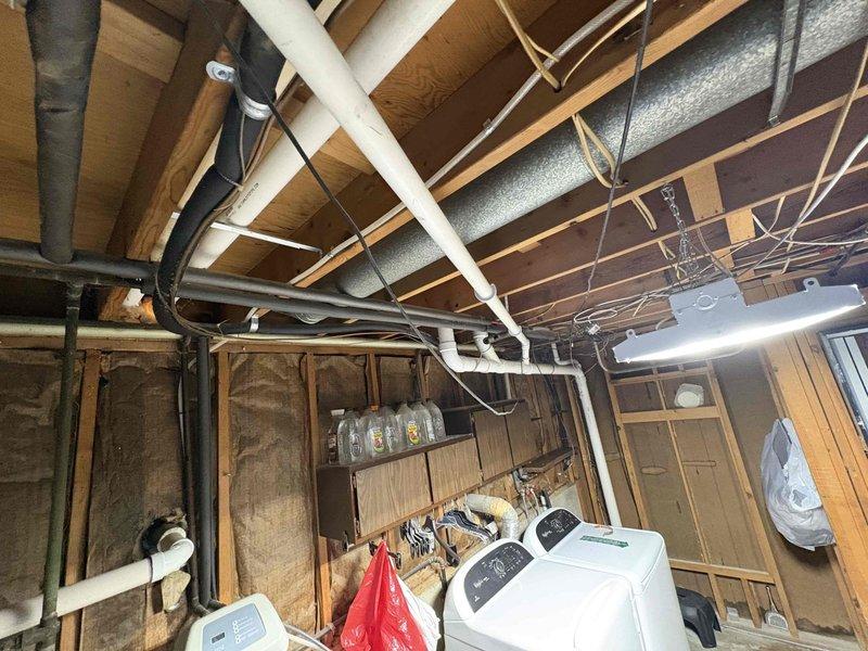 Completed drain repipe installation in residential basement utility area. Installed new PVC drainage piping throughout the basement space, routing lines along ceiling joists and coordinating with existing electrical wiring, HVAC ductwork, and insulation. Verified proper drainage flow and tested all connections to ensure leak-free operation serving the bathroom facilities above.