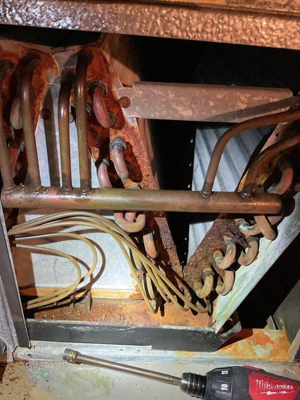 # CP-Cooling Problem - Bryant System

Responded to service call for approximately 20-year-old Bryant split system with inadequate cooling performance. Upon inspection, discovered severely corroded evaporator coil with extensive rust throughout the interior components, indicating long-term moisture exposure and deterioration. The refrigerant lines and mounting brackets showed significant oxidation, compromising system integrity and heat transfer efficiency. Documented conditions with photos showing the extent of corrosion on the evaporator assembly and overall system configuration with air handler mounted above the Bryant furnace. Advised customer that the extensive rust damage to the evaporator coil and associated components has severely degraded cooling capacity and system performance, requiring coil replacement or full system replacement to restore proper operation.