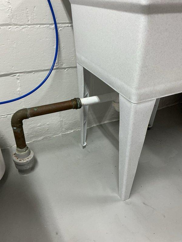 Responded to slow drain at laundry tub and noise from downstairs toilet when upstairs toilet is flushed in 1950s single-family home. Inspected plumbing system including vertical drain lines, copper supply piping, and drainage connections in utility area. Documented existing plumbing infrastructure with photos showing PVC drainage system and copper supply lines for service records.