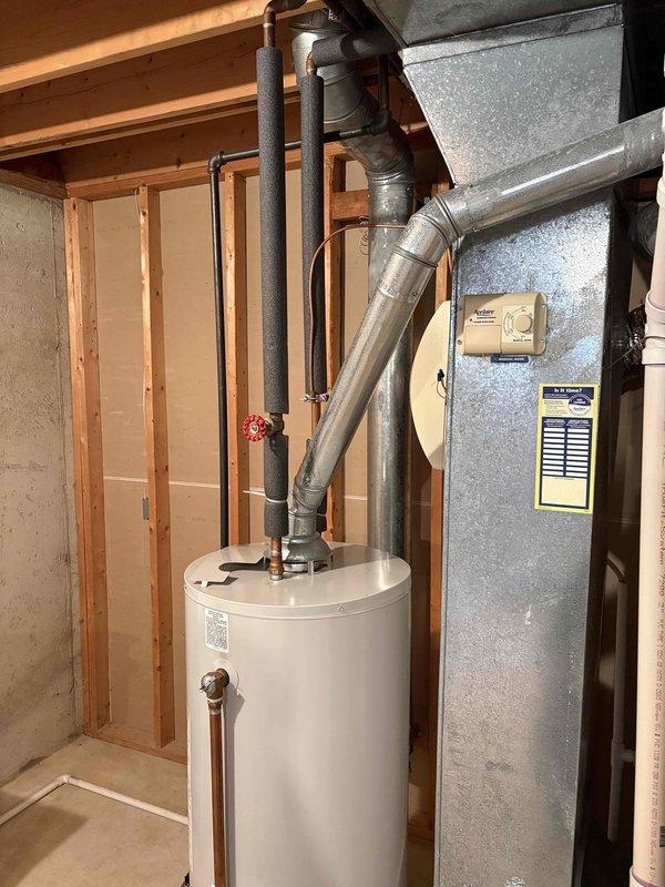 Conducted on-site assessment for new tank water heater installation in residential basement utility area. Evaluated existing water heater configuration, plumbing connections, venting system, and clearance requirements in relation to adjacent HVAC equipment. Documented current installation setup including pipe routing, gas connections, and exhaust ductwork for replacement specifications and provided estimate for complete water heater replacement.