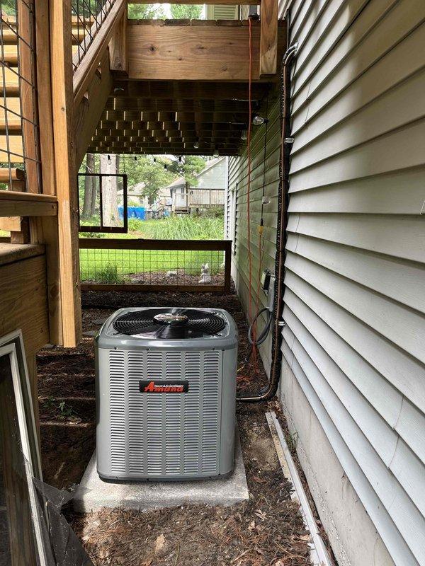 Completed full air conditioning system replacement including outdoor Amana condenser unit installed on concrete pad in side yard location and connected to existing furnace system in basement mechanical room. Ran refrigerant lines from outdoor unit to indoor air handler, completed all electrical connections, and performed system startup and testing. System commissioned and verified operational with proper airflow and cooling performance.
