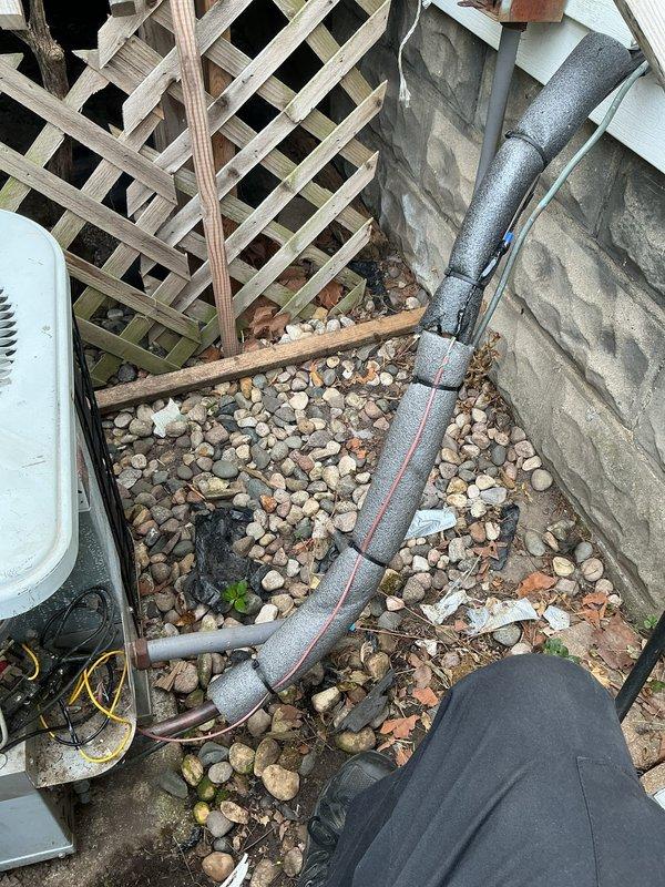 Responded to no-cooling call on 10-year-old residential AC system. Upon arrival, performed visual inspection of outdoor condensing unit and refrigerant line set. Unit showed signs of age and weathering with visible discoloration on exterior casing. Inspected condenser coil through protective grille and noted general condition of equipment. Examined refrigerant lines running from condenser to building, verifying insulation integrity and proper mounting. Checked electrical connections at outdoor disconnect and condensing unit. Documented equipment condition and installation setup with photos for service records. Unit location showed minimal maintenance over time with debris accumulation around base. Refrigerant lines properly insulated and secured to exterior wall with appropriate brackets. Verified contact information for follow-up communication regarding system diagnosis and repair recommendations.