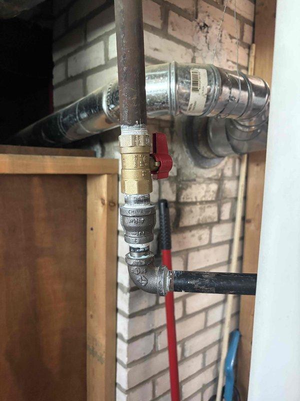 Returned to property to replace faulty gas shutoff valve on black iron pipe gas line. Removed existing valve assembly and installed new brass ball valve with red handle, ensuring proper threading and secure connections to vertical and horizontal pipe sections. Tested valve operation and verified proper shutoff function with no gas leaks detected.