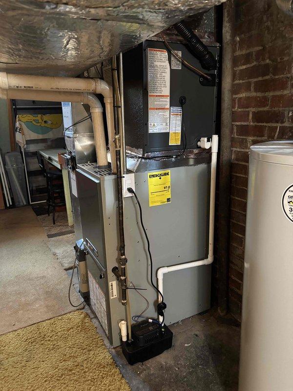 Completed full air conditioning system replacement at residential property. Removed existing outdoor condensing unit and installed new high-efficiency AC condenser on concrete pad with proper refrigerant line connections and electrical disconnect. Installed new evaporator coil at furnace location in basement, integrated with existing gas furnace system. Ran refrigerant linesets through exterior wall with appropriate insulation and PVC line hide. Connected condensate drainage lines with proper pitch and termination. Installed new thermostat wiring and verified all electrical connections meet code requirements. Pressure tested refrigerant lines for leaks, evacuated system to proper vacuum levels, and charged unit to manufacturer specifications. Verified proper airflow across evaporator coil and through ductwork. Started system and confirmed cooling operation, checked temperature split across coil, and monitored system pressures during operation. Reviewed thermostat operation and system c