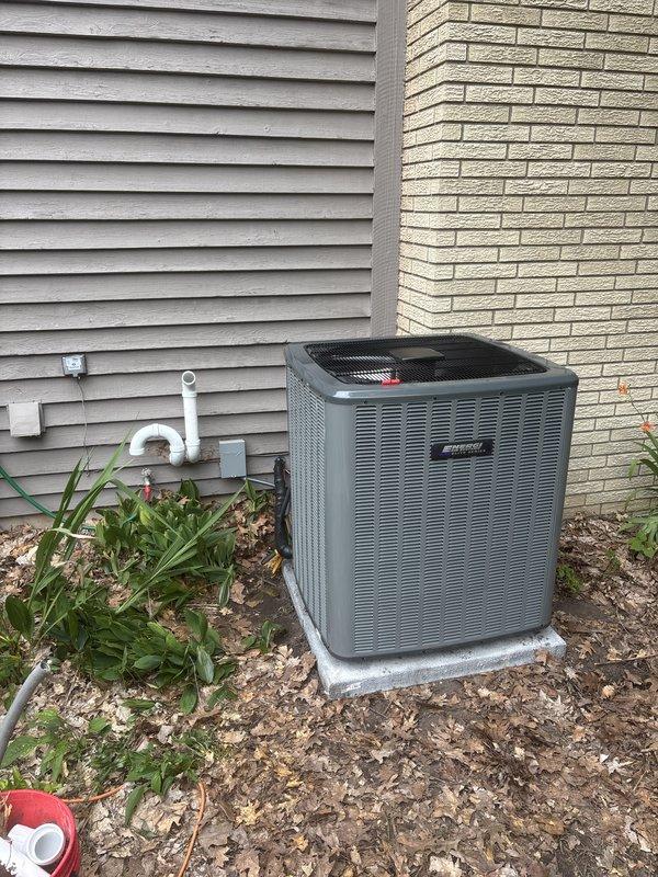Completed full HVAC system installation including new Amana furnace and outdoor condensing unit. Installed furnace in utility area with proper venting and ductwork connections, mounted Aprilaire humidifier on supply plenum with PVC drain line routed to floor drain. Set outdoor AC condenser on concrete pad between building exterior walls, completed refrigerant line set connections and electrical hookup with disconnect box mounted on siding. Verified all ductwork transitions secure, tested system startup and operation, confirmed proper airflow and temperature differential across coil. Installation meets manufacturer specifications and local code requirements.