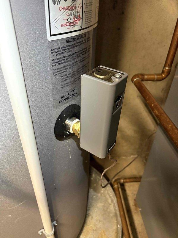 Responded to water leak originating from the temperature control assembly on an 8-year-old Utica WT 11 water heater manufactured in 2027. Diagnosed failed thermocouple/temperature sensor at the aquastat connection point causing water seepage. Replaced defective Squire SIT Model 6 thermocouple assembly with new OEM component, ensuring proper connection to control box and secure mounting at brass valve port. Verified all copper piping connections for integrity, tested system operation, and confirmed leak resolution with no further water discharge from control assembly.