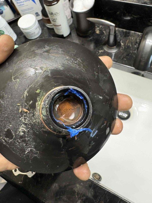 Responded to service call for leaky shower head in thirteen-year-old residential property, with leak reported as ongoing for approximately one month. Upon arrival, confirmed leak was isolated to shower head fixture only. Removed and inspected shower head assembly, identifying significant mineral buildup, sediment accumulation, and deteriorated thread seal tape as primary causes of the leak. The internal threading and seal surfaces showed brown discoloration and heavy deposits consistent with hard water conditions and extended use without maintenance. Cleaned affected components, removed old thread sealant material, and applied fresh thread seal tape to ensure proper seal. Reinstalled shower head assembly with proper torque specifications. Tested fixture operation and confirmed leak was fully resolved with no drips or seepage present. Advised property owner on recommended maintenance intervals to prevent future buildup issues.