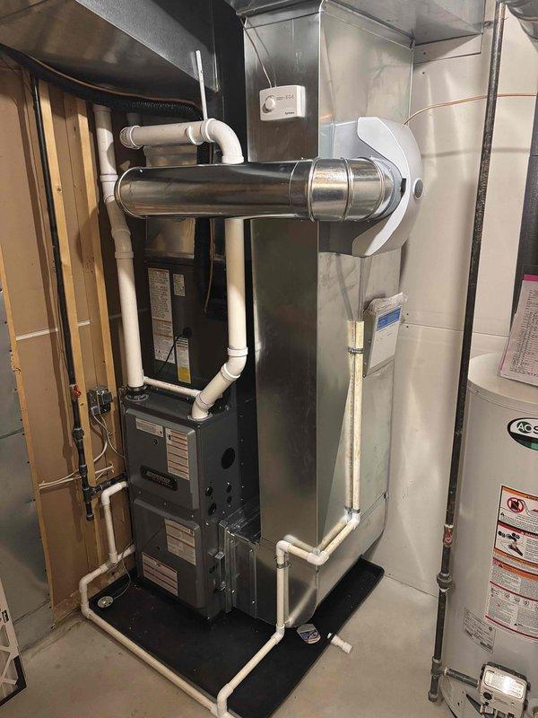 Completed full HVAC system installation including new black furnace unit with PVC venting and drainage piping configuration in basement utility area. Installed outdoor condensing unit on prepared gravel pad with proper electrical disconnect and secure mounting. Connected metallic ductwork to furnace, ensured all venting meets code requirements, and verified system operational with proper airflow and refrigerant charge.