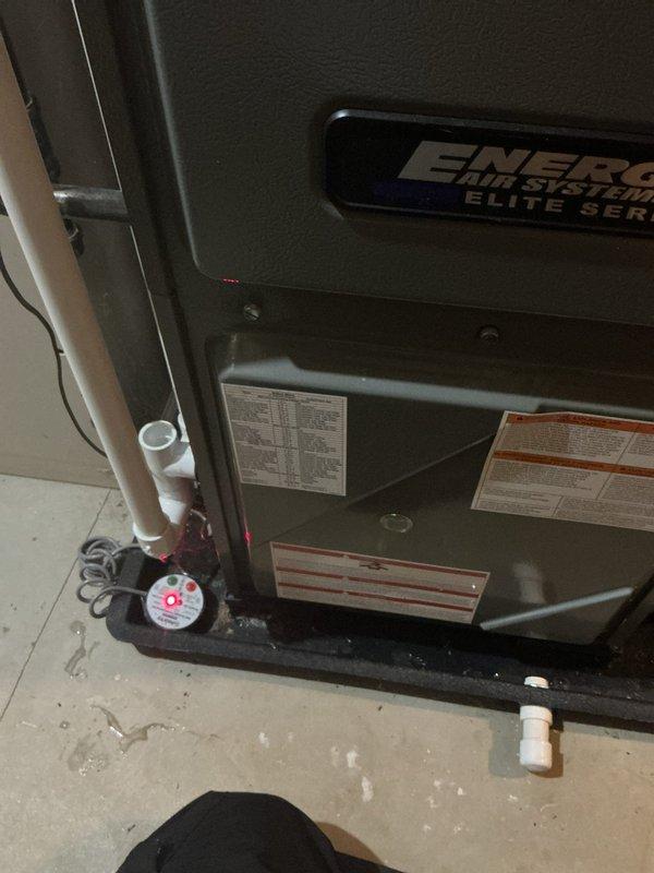 Responded to no cool call and found moisture detected in furnace with red sensor light illuminated. Upon inspection, discovered water accumulation in bottom of Energy Systems Elite Series furnace unit. Investigated condensate drainage system including PVC and copper piping connections at base of unit. Removed and inspected air filter which appeared clean and in good condition. Addressed moisture issue and cleared sensor fault to restore normal system operation.