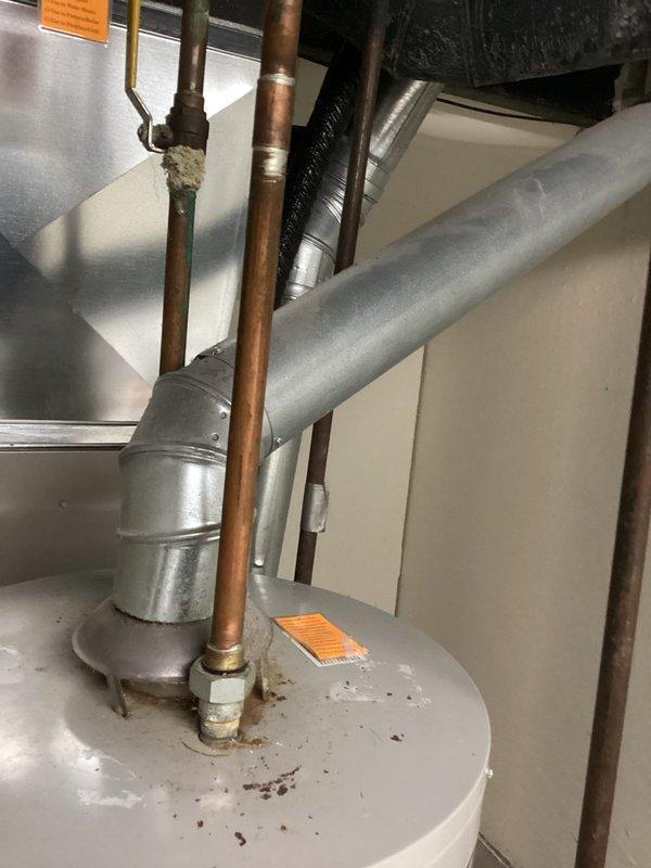 Completed estimate for water heater replacement at 50-year-old residential property. Existing tank-style water heater showing signs of age with visible corrosion and rust staining around pipe connections. Unit located in basement mechanical room alongside furnace system with copper supply lines, brass fittings, and metallic venting in place. Documented current installation configuration and confirmed customer contact information for future coordination of replacement work.