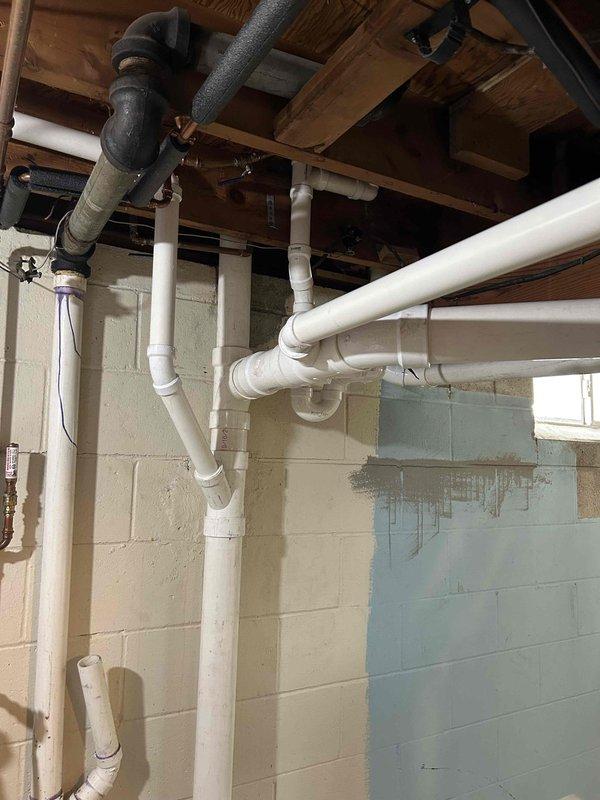 Completed comprehensive drain repipe project in basement utility area, installing new white PVC drainage system with proper elbows, joints, and connections throughout exposed ceiling joists. All piping was secured with appropriate brackets and straps to wooden structural members, ensuring code-compliant installation and proper drainage flow. Work completed within scheduled timeframe with all connections tested and verified operational.