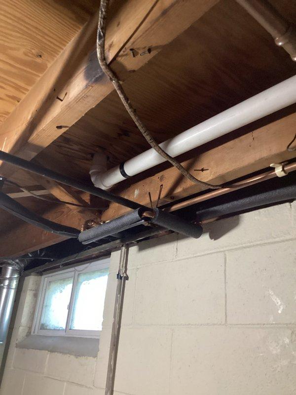 Completed comprehensive drain repipe project in basement utility area, installing new white PVC drainage system with proper elbows, joints, and connections throughout exposed ceiling joists. All piping was secured with appropriate brackets and straps to wooden structural members, ensuring code-compliant installation and proper drainage flow. Work completed within scheduled timeframe with all connections tested and verified operational.
