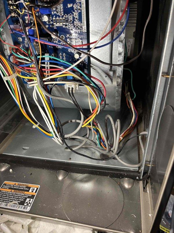 Responded to no cooling call on a 4-year-old Carrier system with no heating or cooling operation throughout the home. Upon arrival, inspected the outdoor condenser unit and indoor control board assembly. Documented system components including the control board with multiple low-voltage wire connections, circuit board condition, and overall wiring configuration. Photographed the outdoor unit positioned on concrete pad showing normal wear and the interior control panel section displaying the blue circuit board with various colored wire connections to terminals. System evaluated and photos captured for diagnostic documentation.