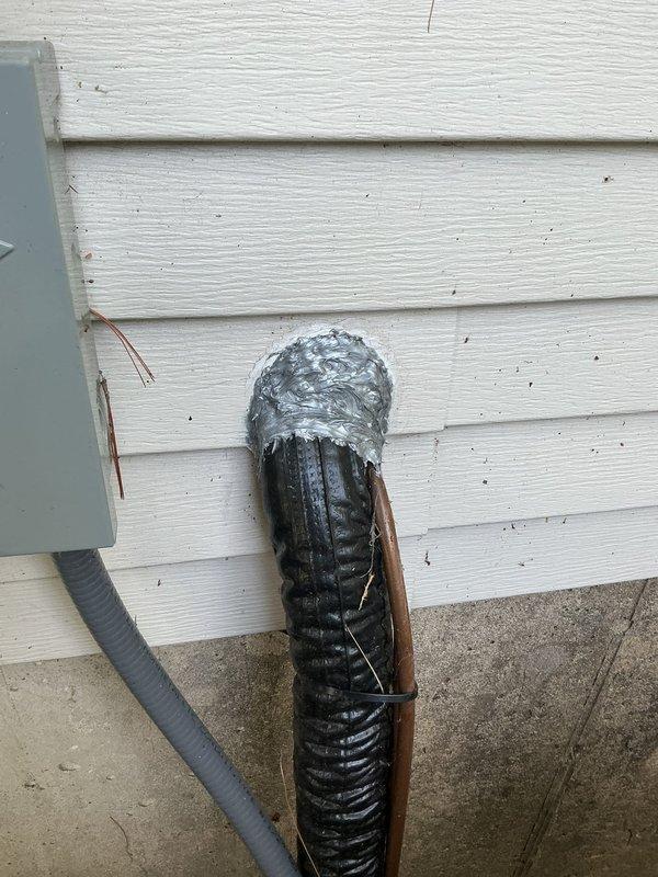 Completed sealing work on HVAC system exterior penetrations under one-year warranty. Applied caulking and expanding foam sealant around refrigerant line set and exhaust conduit penetrations through building envelope where gaps were present from initial installation. Secured conduit with copper fastening strap and applied metallic tape for additional weatherproofing. All penetrations through vinyl siding now properly sealed to prevent air and moisture infiltration.