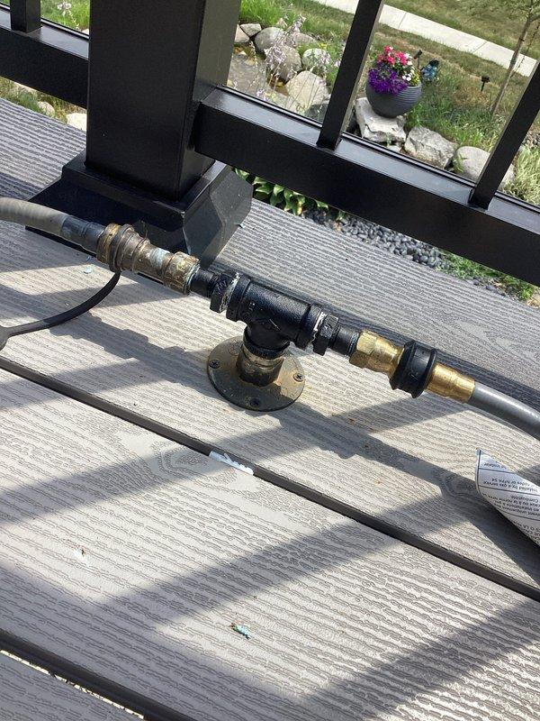 Returned to property to correct gas line installation in crawl space and deck area. Installed proper pipe supports and hangers along floor joists to secure yellow flexible gas line per code requirements. Replaced gas line fittings at deck-mounted connection point, installing new brass fittings and T-joint assembly with proper flanges secured to deck surface. Painted all exposed black iron pipe and fittings throughout installation for corrosion protection and finished appearance.