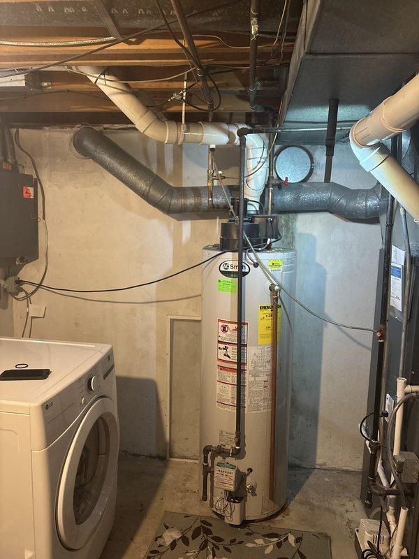 Responded to no hot water complaint on 14-year-old AO Smith water heater with visible corrosion on top connections. Upon inspection, confirmed extensive corrosion at inlet/outlet connections and determined unit had reached end of serviceable life. Documented existing installation configuration including copper supply lines, electrical connections, and proximity to HVAC ductwork and laundry appliances in basement utility area.