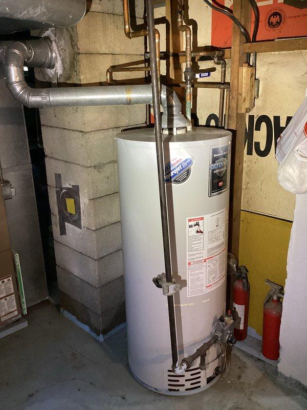 Provided estimate for replacement of 13-17 year old residential water heater exhibiting active leaking from bottom of tank. Upon inspection, documented existing standard cylindrical water heater installation in basement utility room with copper supply and distribution piping, proper venting, and electrical connections. Unit showed signs of age-related deterioration with bottom tank failure requiring full replacement rather than repair.