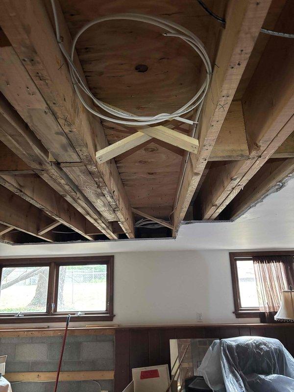 Completed comprehensive two-day structural ceiling repair involving removal of damaged drywall sections to expose and assess ceiling joists and framing members. Installed new diagonal bracing and reinforcement supports between existing joists to strengthen compromised ceiling structure. Removed deteriorated materials, secured all framing connections, and protected furnishings with plastic sheeting throughout the work area. Created access openings to address structural concerns and prepare surfaces for final drywall installation and finishing work.