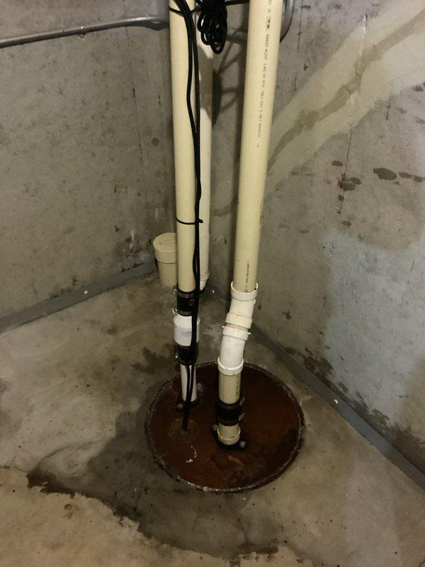 Responded to service call for sump pump system unable to keep up with washing machine discharge. Upon inspection, found dual-pipe sump pump installation with visible water accumulation in pit and moisture staining on surrounding concrete floor indicating inadequate pumping capacity or potential system malfunction. Documented existing conditions including pump configuration, electrical connections, and evidence of water management issues in basement utility area.