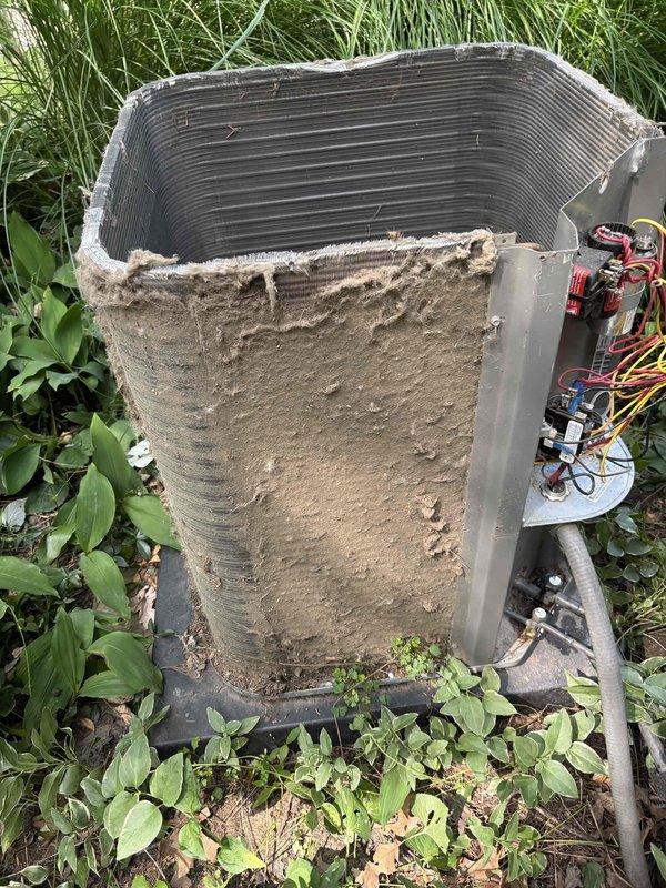 Completed annual cooling maintenance on a 6-year-old Lennox air conditioning system. Upon arrival, found outdoor condenser unit heavily soiled with thick accumulation of dirt, dust, and debris coating exterior panels and surrounding vegetation significantly overgrown around equipment. Performed comprehensive tune-up including thorough cleaning of condenser coils which showed dark buildup on horizontal fins, cleared debris from unit exterior and base, and trimmed back encroaching grass and plants to restore proper airflow clearance around unit. Inspected electrical components, refrigerant lines, and control board for proper operation. Verified system operational performance following cleaning and maintenance procedures. Unit restored to optimal operating condition with improved airflow and heat transfer efficiency.