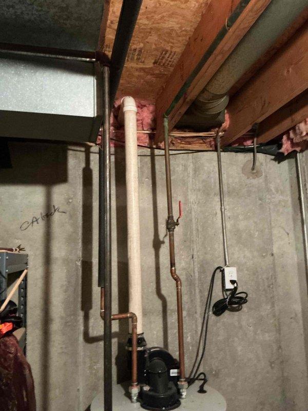 Conducted water heater replacement estimate for 50-gallon tank unit in residential basement location. Documented existing plumbing configuration including copper supply lines, PVC drain piping, and current mechanical installations within unfinished basement space featuring exposed floor joists and concrete foundation walls. Photographed existing conditions to provide comprehensive assessment for replacement specifications and installation requirements.