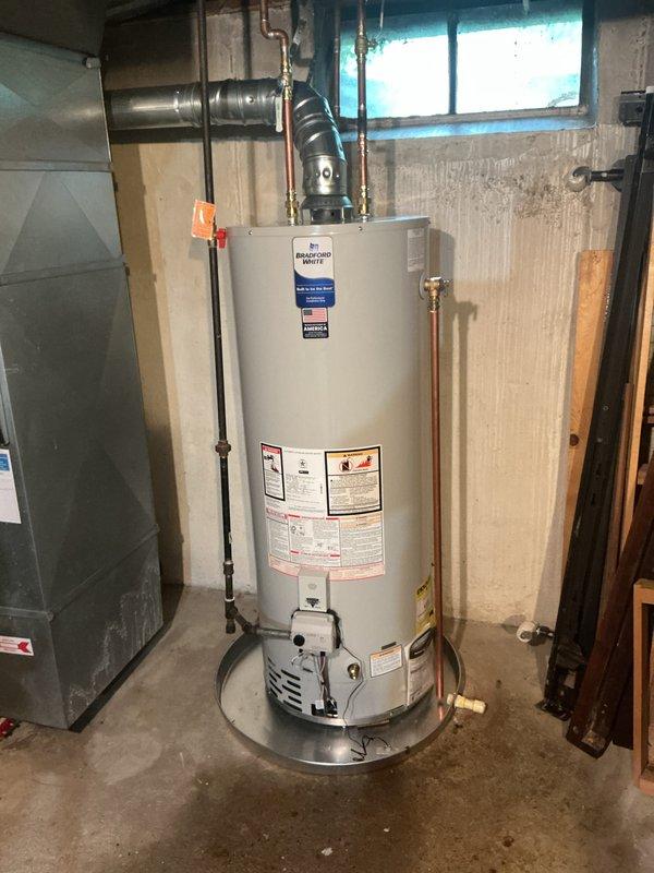 Completed installation of a 50-gallon natural gas Bradford White water heater (Model BN250T6N) with a 40,000 BTU/H input capacity. The unit was properly positioned in the utility area with all necessary connections completed, including copper water supply lines, black iron gas piping with shut-off valve, and metal exhaust venting from the top of the unit.