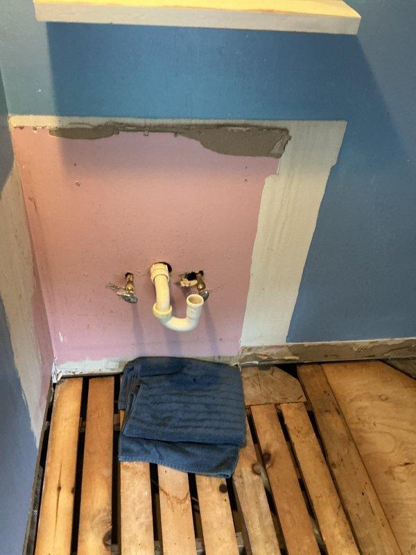 Conducted on-site assessment for bathroom remodeling project requiring multiple plumbing estimate options. Documented existing conditions including exposed floor joists, recessed alcove with visible PVC drain assembly and P-trap configuration, and wall-mounted shut-off valve. Photographed current plumbing infrastructure and construction state to prepare comprehensive estimate proposals for complete bathroom renovation scope.