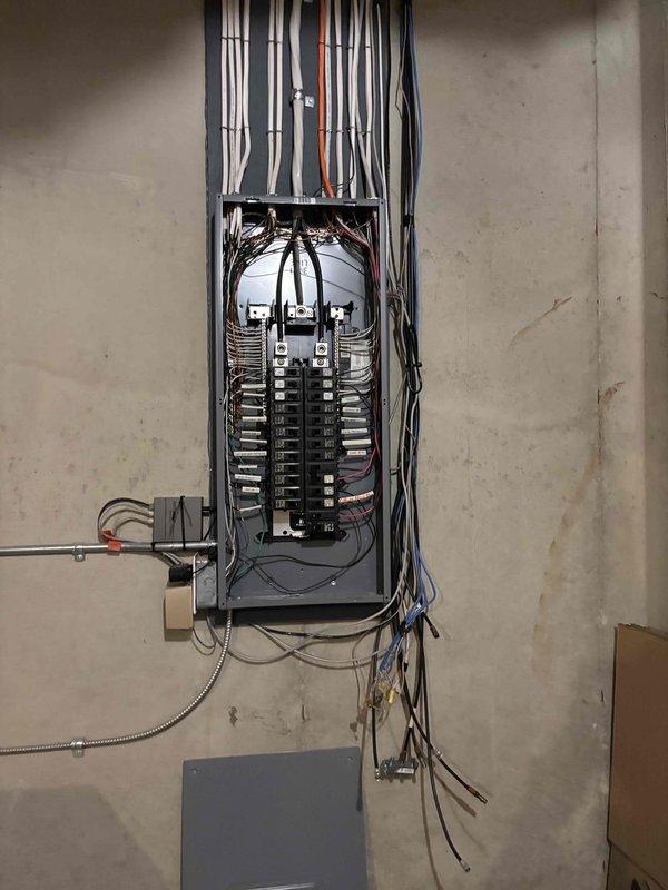 Evaluated electrical panel installation and existing wiring configuration to provide estimate for relocating an extension cord currently running underneath porch area. Documented current electrical panel conditions in both utility room and main living space, noting circuit breaker arrangements, wire routing, and connection points to determine proper method for safely relocating power source and eliminating exposed cord hazard beneath porch structure.