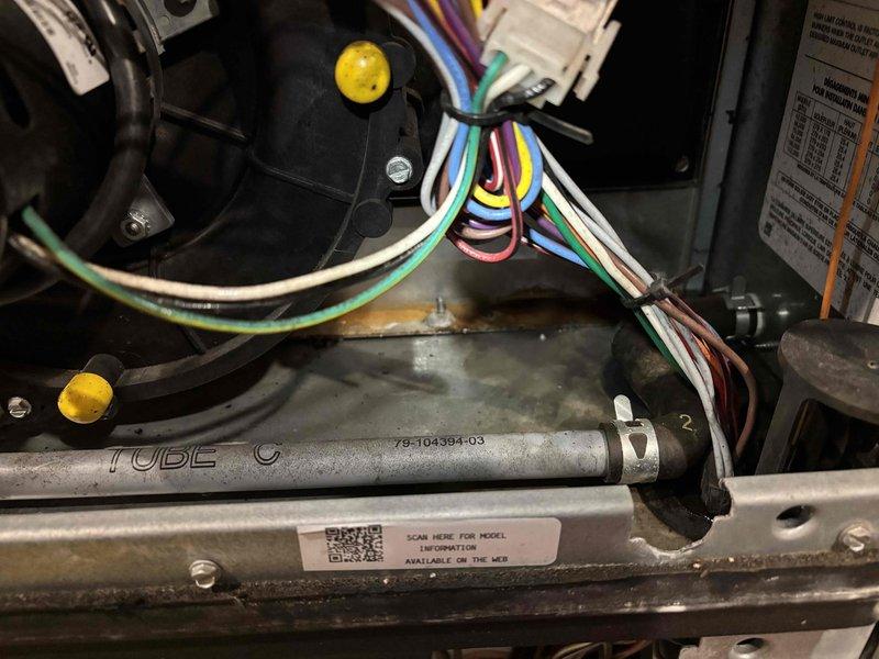 Responded to no-cool complaint on 12-year-old Ruud HVAC system with water leakage at furnace. Upon arrival, found unit powered off by customer due to water accumulation on floor around base of equipment. Removed access panel to inspect internal components and control board. Identified water pooling beneath unit and placed towels to manage accumulation. Inspected evaporator coil drain system and tubing for blockages or disconnections. Photographed wire bundle connections, control board terminals, and drain tube assembly for documentation. Traced condensate drainage issue to determine source of water leak affecting system operation. System remained off during inspection to prevent further water damage and allow for proper diagnosis of cooling failure and drainage malfunction.